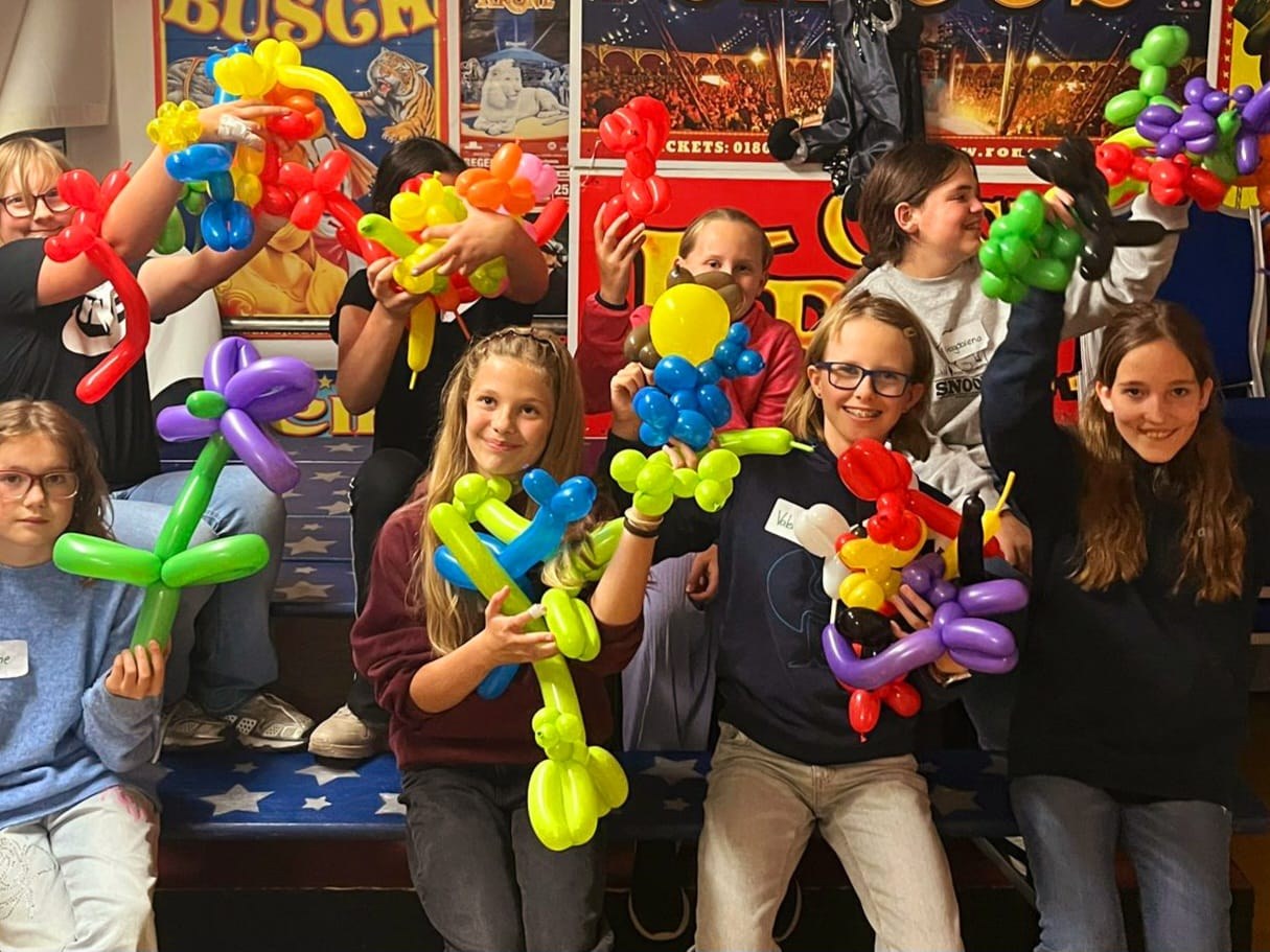 Kinder zeigen stolz ihre selbstgemachten Ballonfiguren
