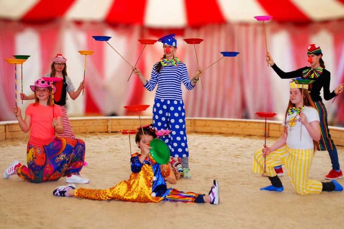 Zauber-Zirkus: Bunte Clownsgruppe mit Zauberteller in der Manege