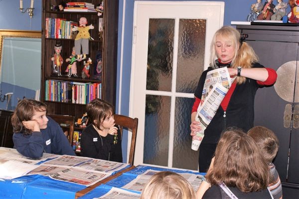 Andrea Hardy zeigt Kindern einen Zaubertrick mit Zeitung