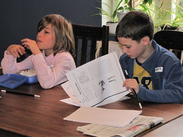 Zwei Kinder üben Zaubertricks mit Zeitung und Papier